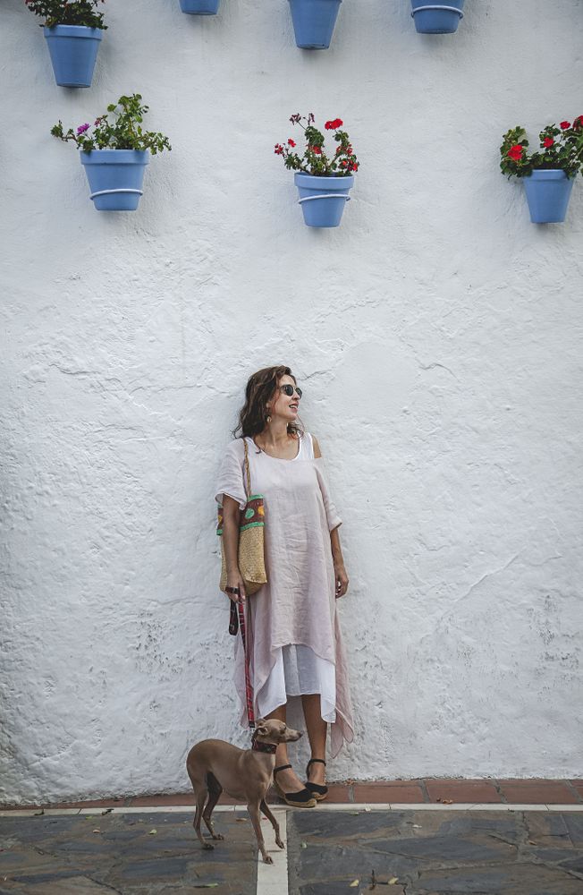 Cheerful female standing with dog near street wall