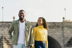 smiling Black couple portrait in front of a bridge
