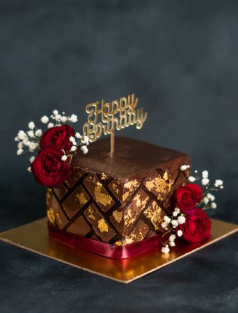 Square chocolate cake with gold leaf, roses and baby’s breath flowers