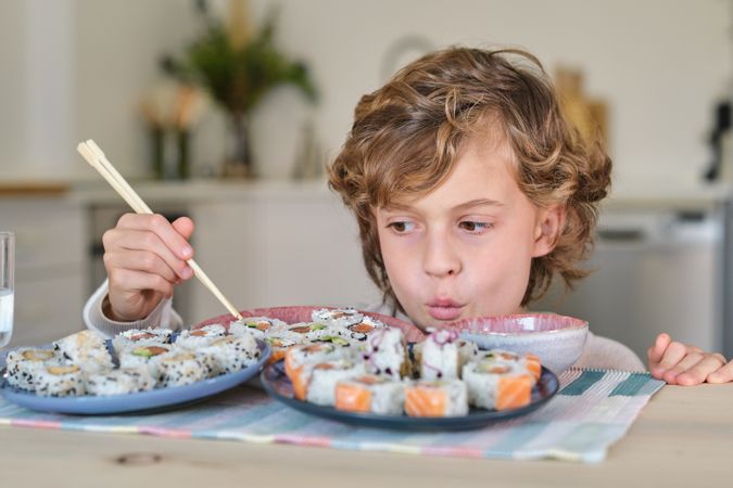 Boy pouting lips and looking at rolls on plate