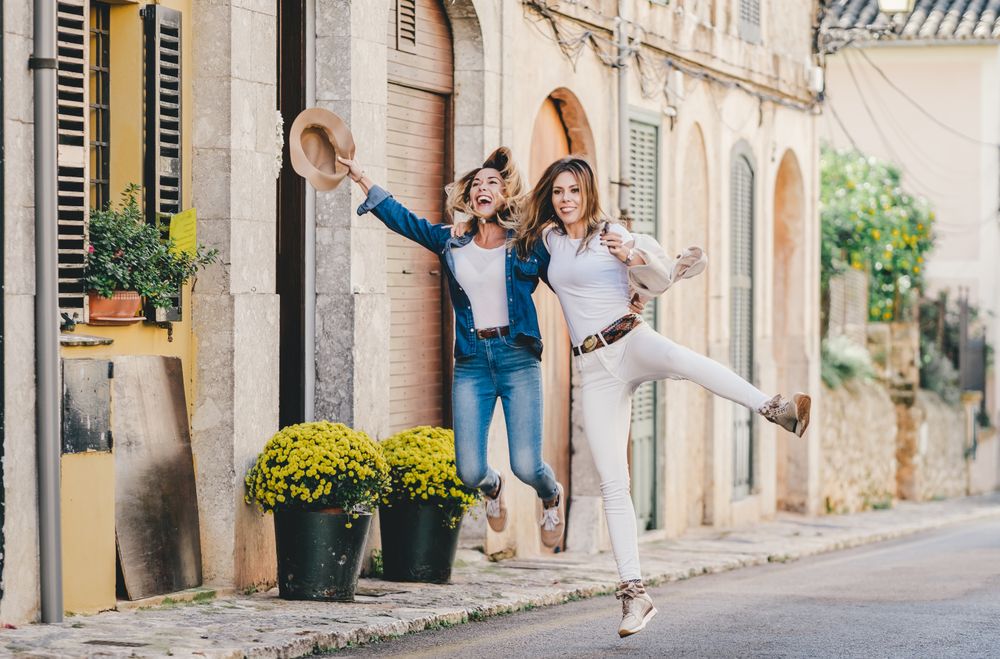 Friends having fun and jumping holding hands in street
