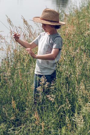 Boy among tall grass near river
