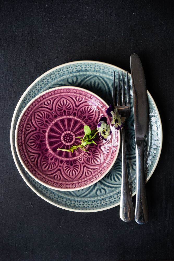 Top view of spring table setting with delicate purple flowers on patterned plate