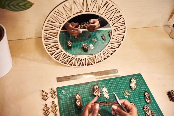 Black jewelry designer working on earrings with mirror