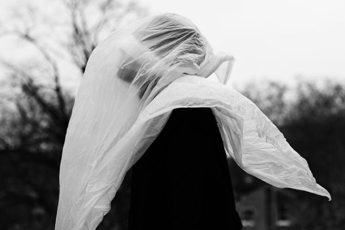 Side view of a person covering their head with plastic bag in grayscale