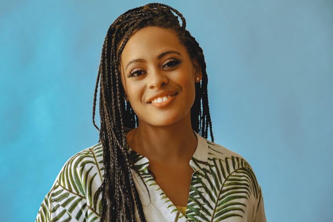 Portrait of relaxed smiling female with long braided hair in printed leaf shirt