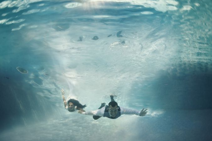 Bride and groom swimming underwater