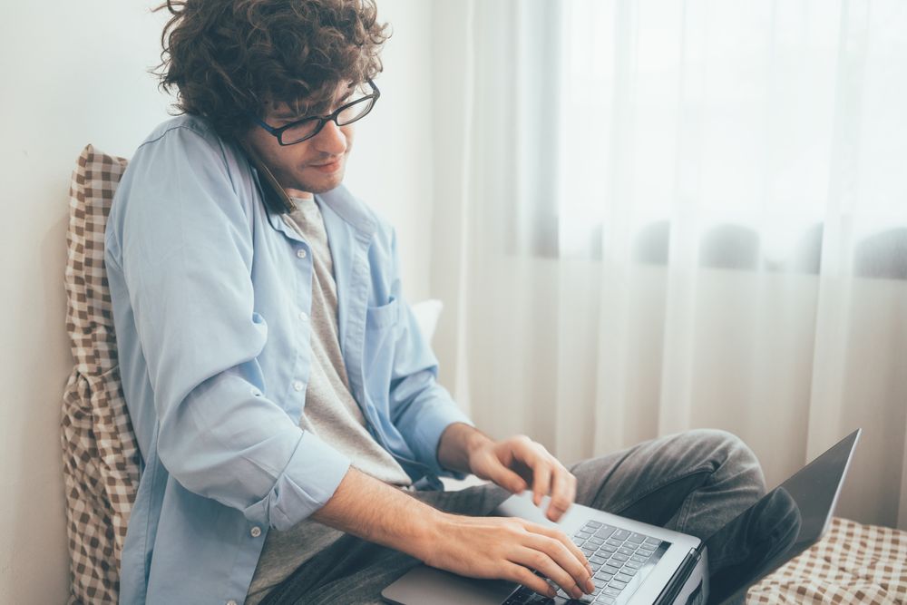 Freelancer man talking on the phone and working on laptop at home