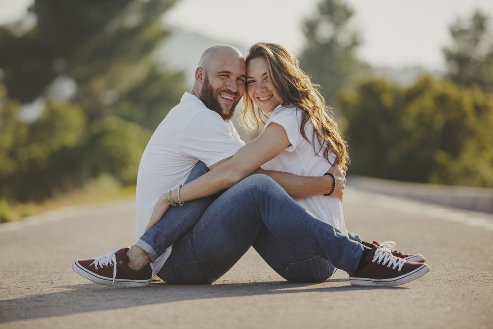 Affectionate couple embracing close sitting on rural road