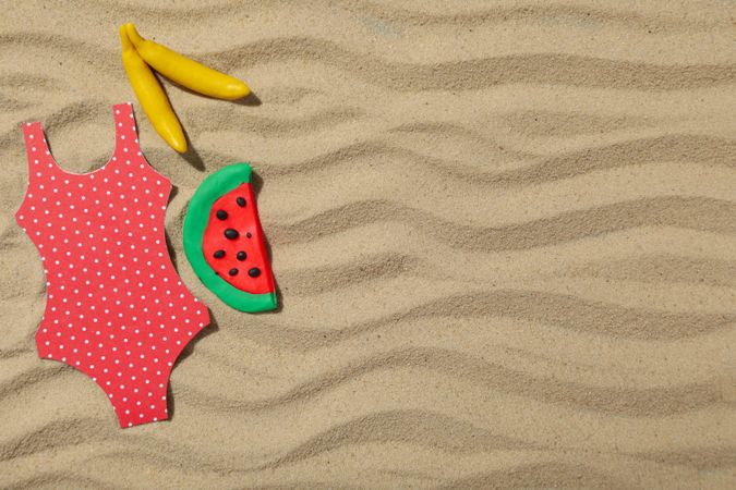 Swimsuit with fruits on the sand, recreation concept.