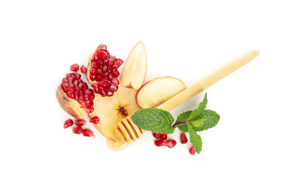 Looking down at honey, pomegranate seeds, mint, and apple