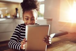Shot of happy girl using tablet in sunny room