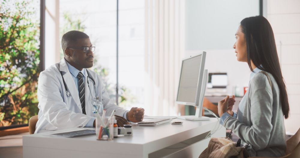 Doctor is Having a Conversation with a Asian Patient, Speaking with Her During Consultation in a Health Clinic.