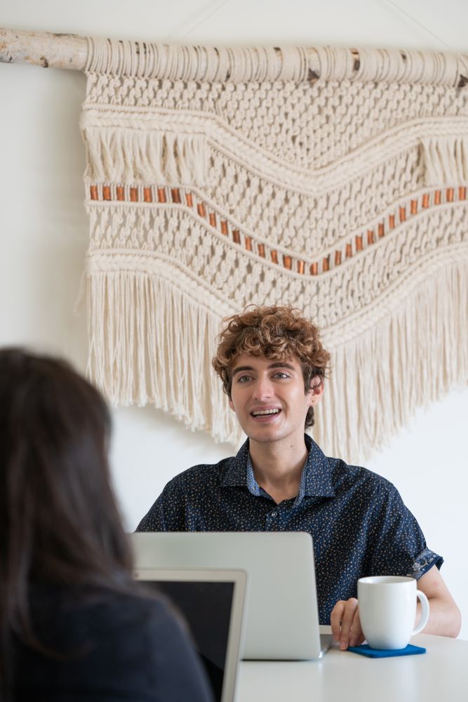 Two people discussing work over their laptops in a bright room
