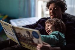Father and boy reading a book in living room