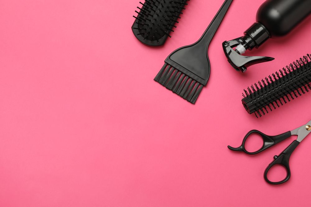Composition with hairdresser accessories on pink background, space for text