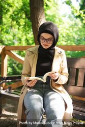 Woman in headscarf engrossed in a book in the park 5arMa4