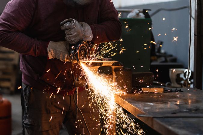 Craftsman grinding metal with grinder in vice