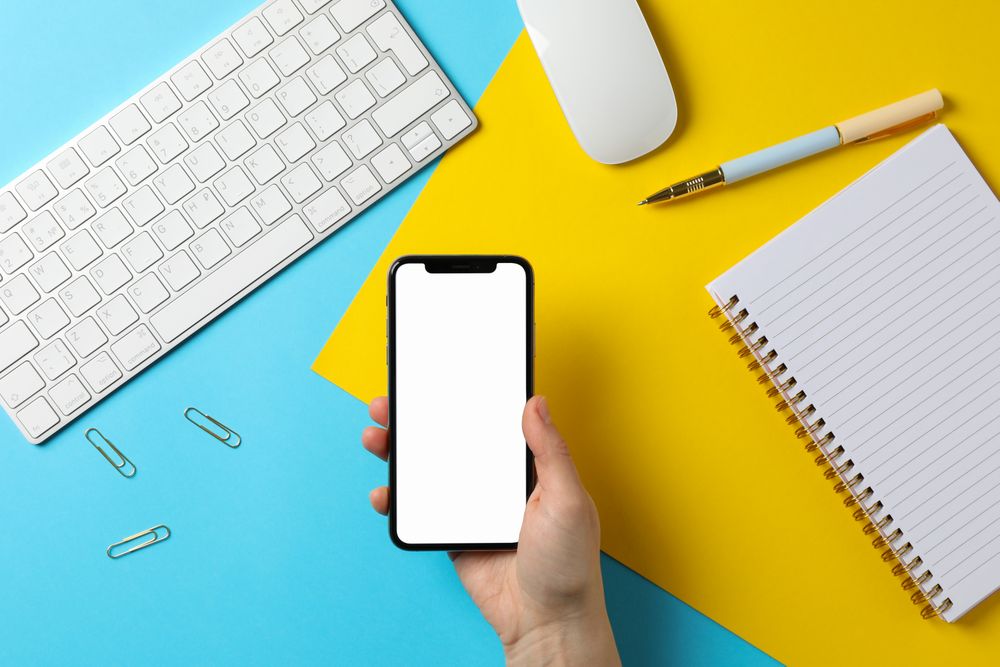 Female holding phone with empty screen. Workplace. Two - tone background