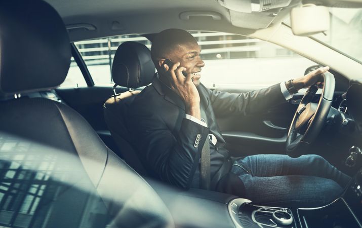 Man smiling talking on the phone and driving