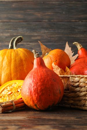 Pumpkins in straw basket on wooden background, copy space