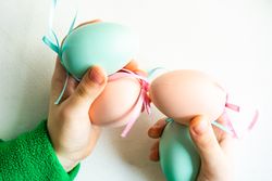 Hands holding pastel egg & pink egg decorations