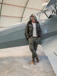 Confident pilot beside retro plane in hangar