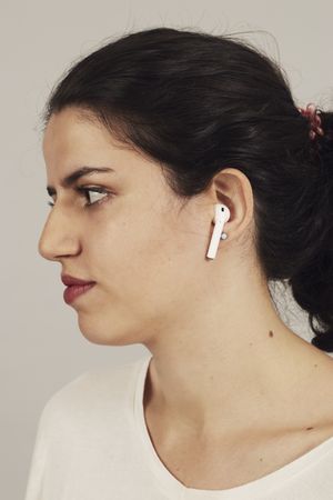 Thoughtful young female athlete listening to music in studio