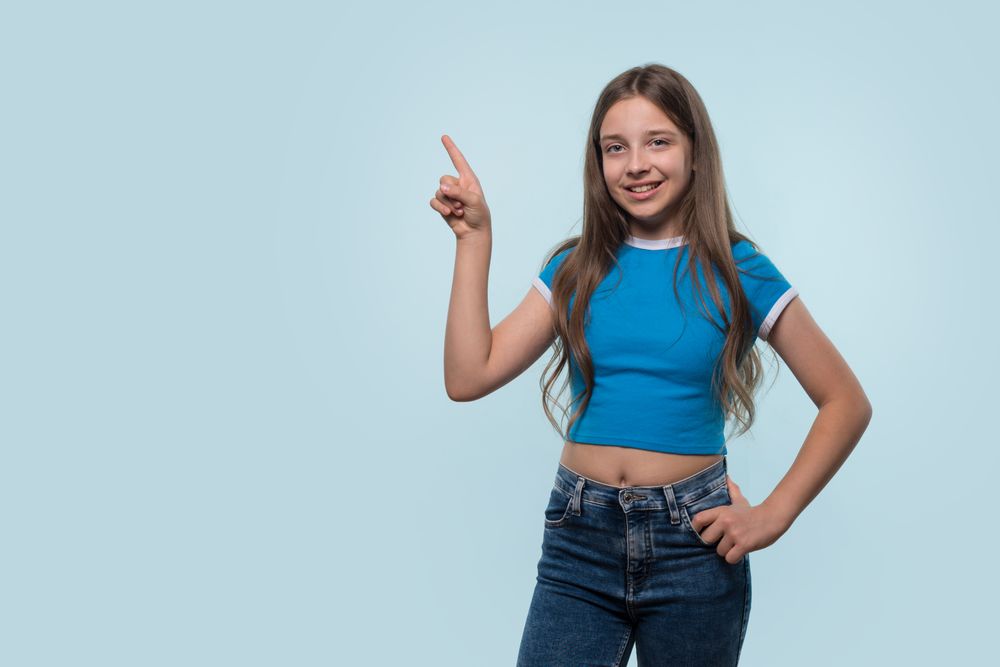 Girl confidently pointing upwards, indicating an idea.