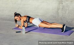 Side view of fit young woman doing planks exercising outdoors in morning 5kmvLb