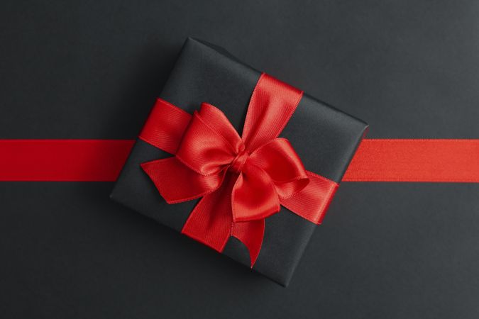 Gift box and red ribbon on dark background