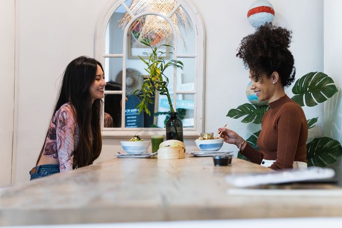 Delighted friendly multiethnic women eating in restaurant