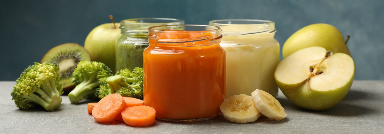 Composition with baby food on gray background, close up