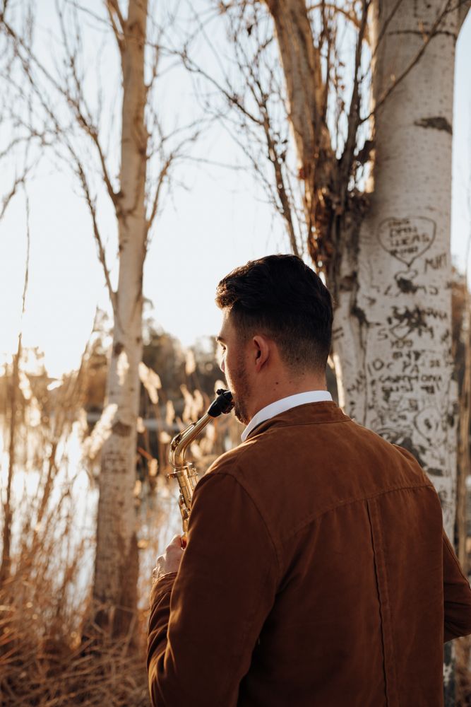 young musician backwards playing the saxophone at sunset