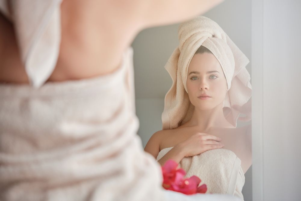 Woman in towel enjoying reflection in mirror in bathroom