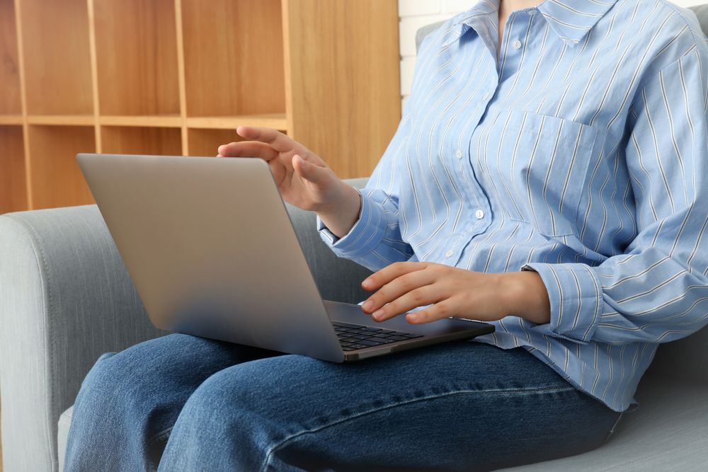 Young woman with laptop sitting on sofa in modern flat