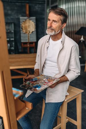 Mature artist with paint palette and easel