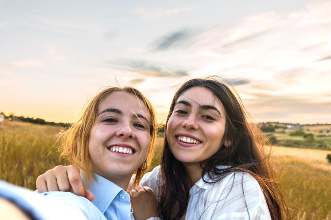 two women selfie on a field at sunset