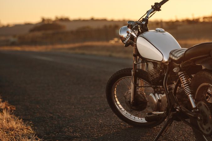 Vintage motorcycle parked on empty rural road at sunset