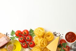 Composition with pasta and ingredients for cooking on plain background, top view