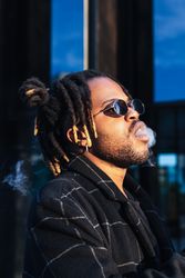Black man exhaling cloud of smoke on street