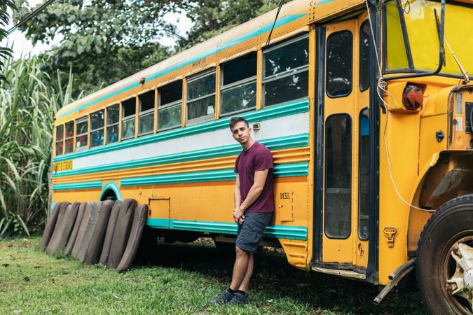 Man leaning on a vintage school bus in reparation