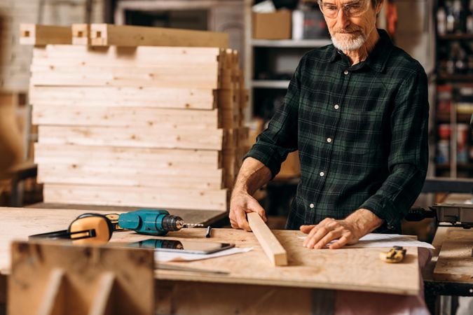 Older male in protective glasses working as a carpenter