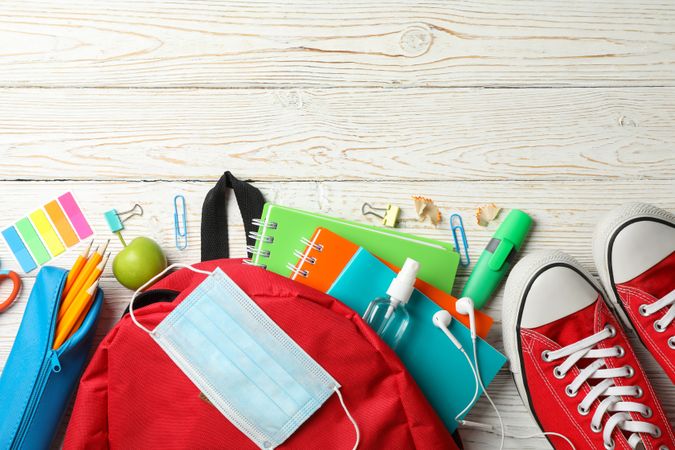 School supplies with medical mask and sanitizer on wooden background