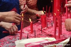 People lighting candles on table for prayer 0J6wZ0