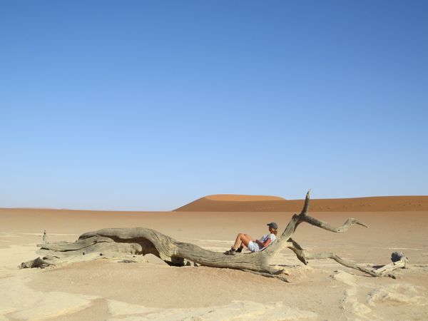 Person lying on tree log in desert