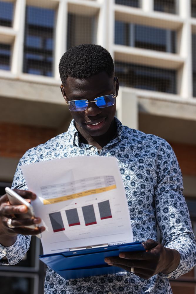 Black businessman with graphics on paper in town