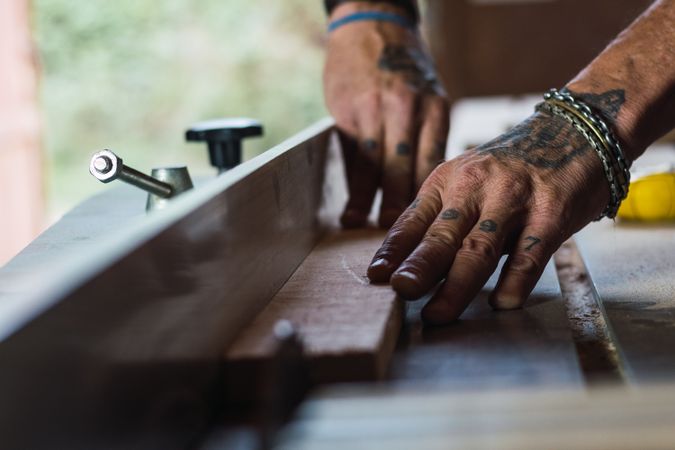 Crop male carpenter cutting wood with circular saw