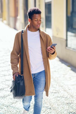 Cuban male walking down street looking at his phone