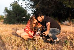 Happy couple with friendly cute dog resting outdoors